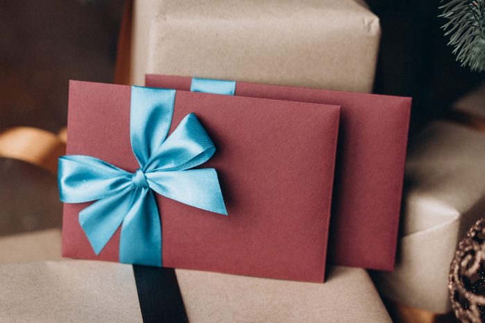 Gift cards in burgundy envelopes with blue bows among other gifts