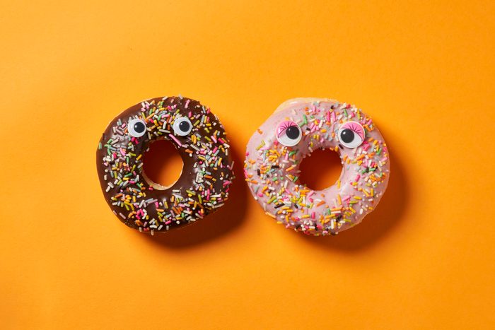 Two Sprinkle Donut with googly eyes on orange background