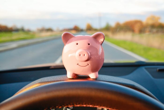 piggy bank sitting on the dashboard of a car on a road trip
