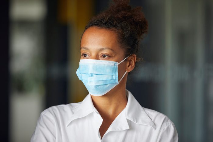 Portrait of businesswoman wearing light blue protective mask looking at distance