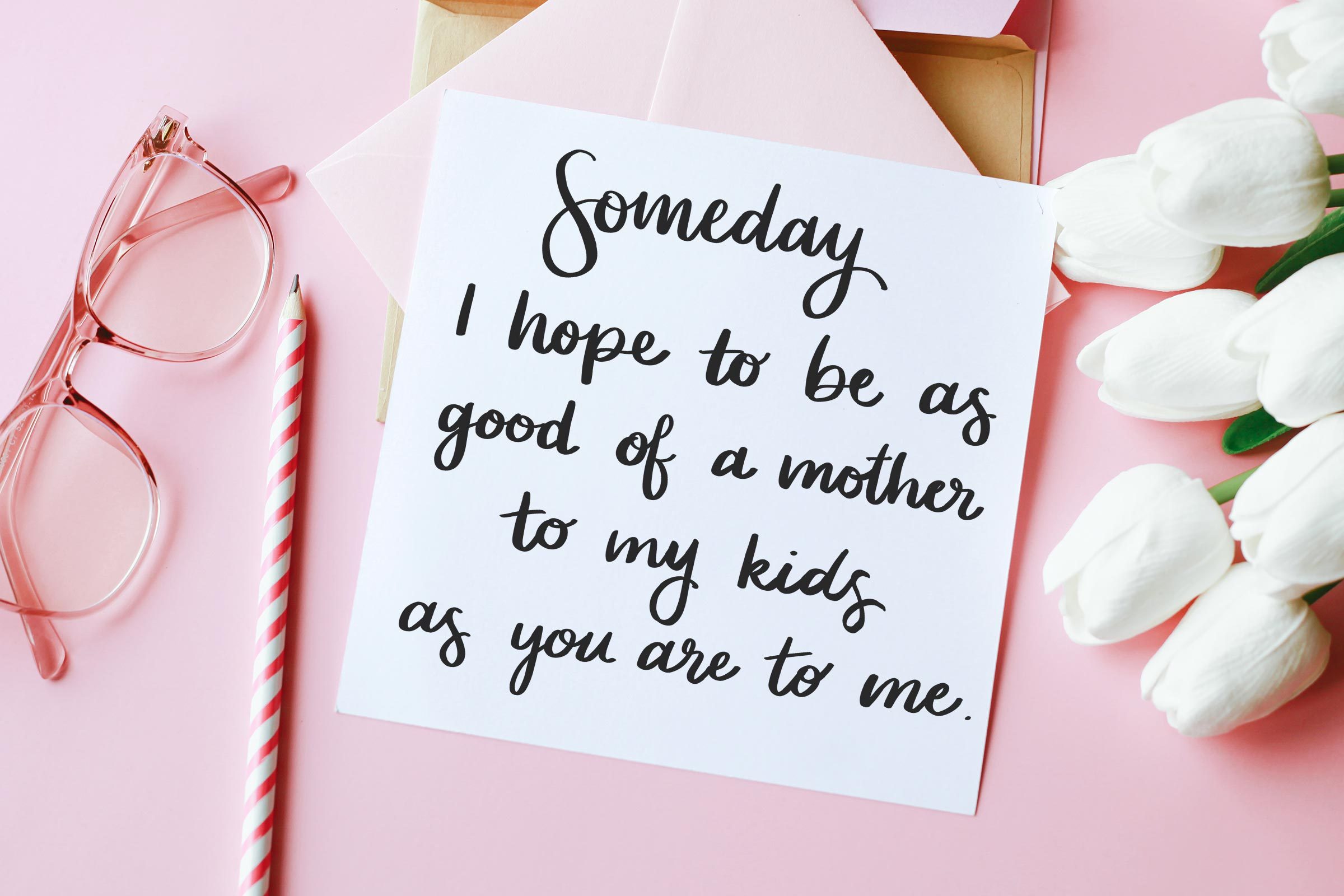 tarjetas, vasos, lápices, tulipanes blancos sobre un fondo rosa.  la tarjeta dice, "Algún día, espero ser tan buena madre para mis hijos como tú lo eres para mí."