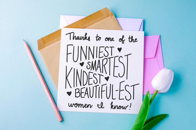 stack of cards, pencil, and white tulip on blue background. top card reads, "thanks to one of the funniest, smartest, kindest, beautiful-est women i know!"