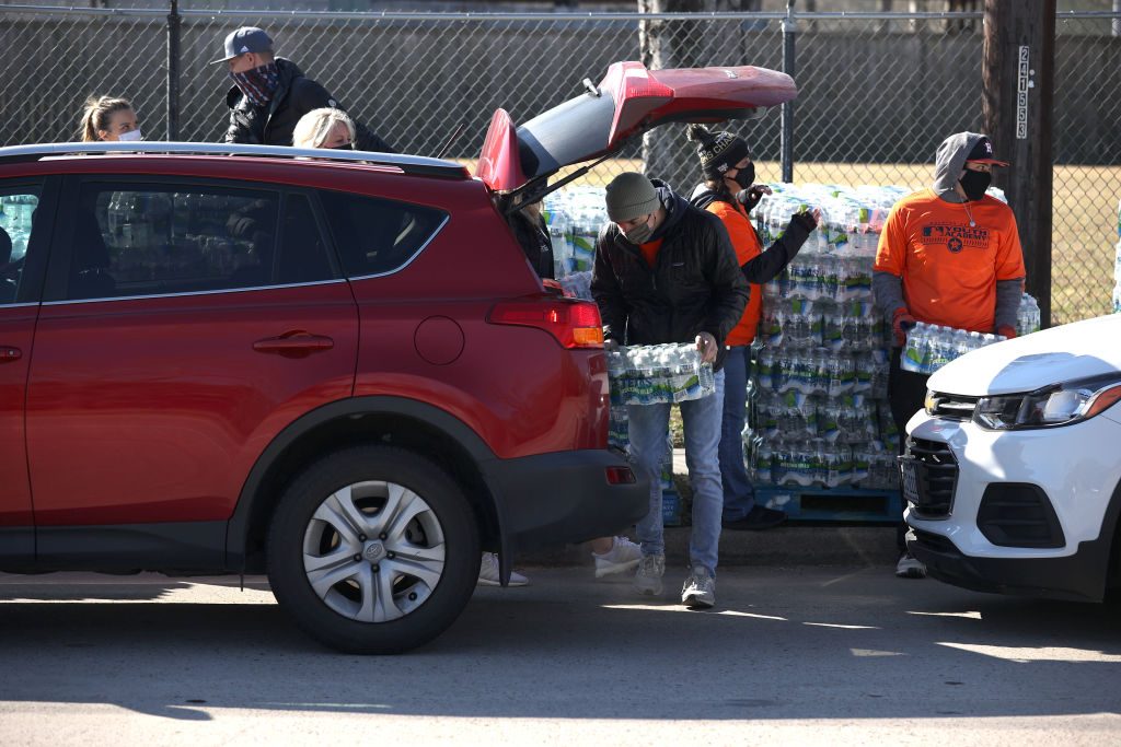 Los voluntarios cargan cajas de agua en un automóvil durante una distribución de agua en la Academia Juvenil de los Astros el 20 de febrero de 2021 en Houston, Texas.