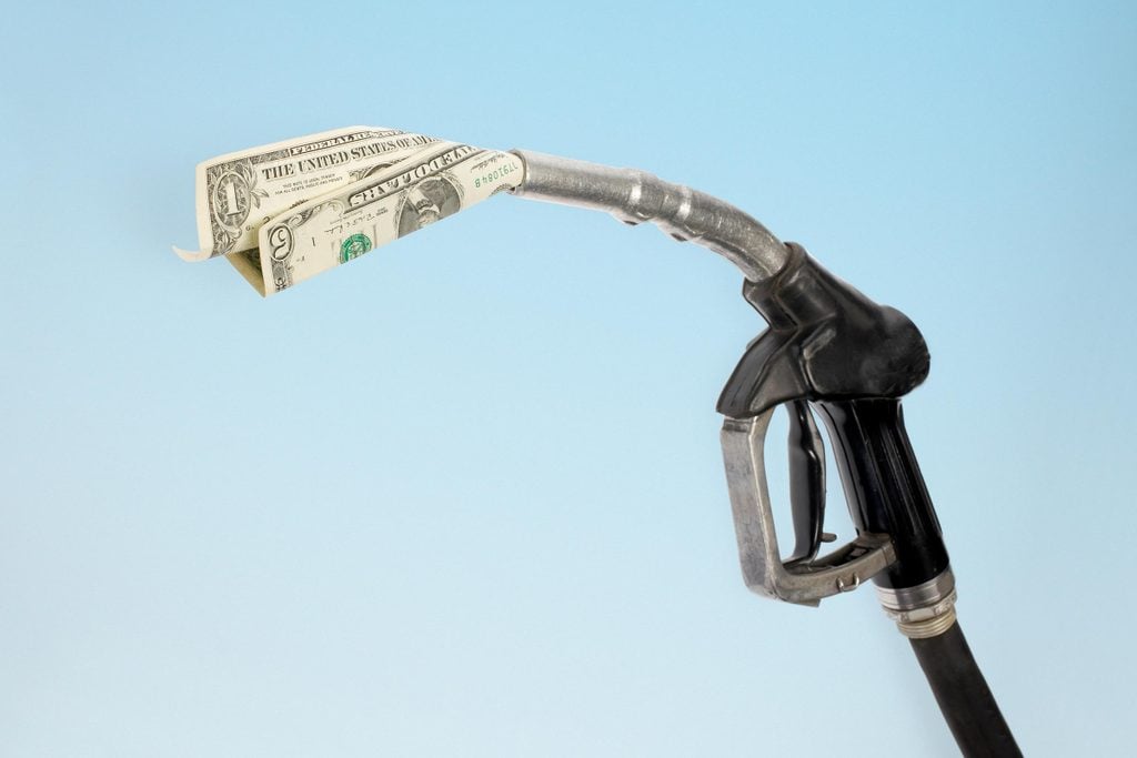 gas pump with a one dollar bill and a five dollar bill coming out of the end of the pump