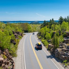 Cars driving on road in Acadia National Park, Maine, USA. One car holds a canoe on its roof.