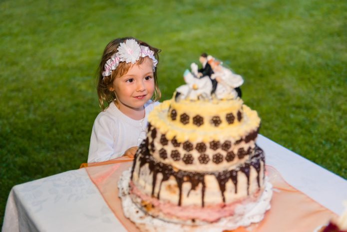 Sweet little girl looking up at a wedding cake