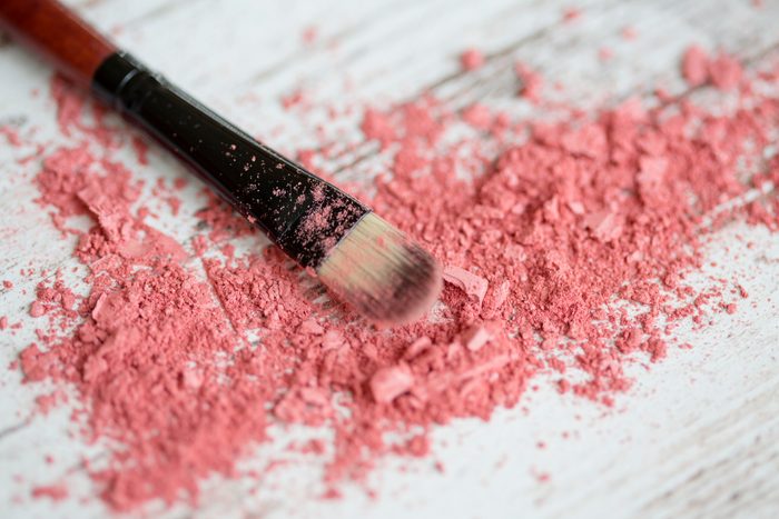 Close-up of a makeup brush laying in crushed cosmetics