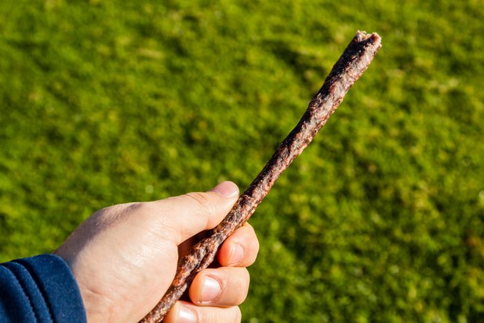 A hand holding a stick of droewors (biltong). This is a popular South African snack.