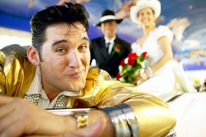 elvis impersonator close to the camera with bride and groom in the background