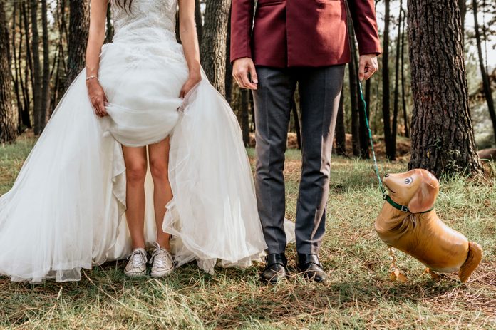 Low section of bride and groom in forest with funny dog-shaped balloon