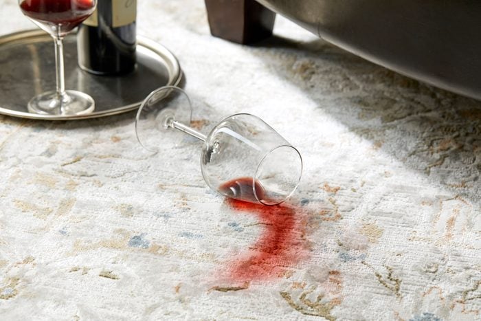 spilled glass of red wine creating a stain on a rug