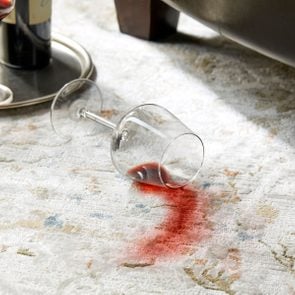 spilled glass of red wine creating a stain on a rug