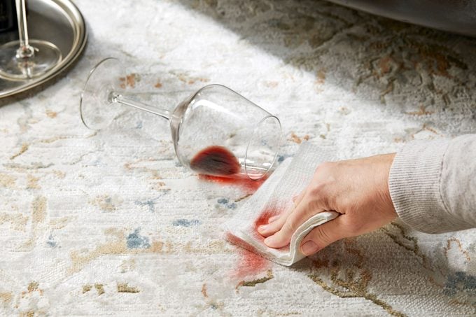 hand blotting red wine stain on a rug