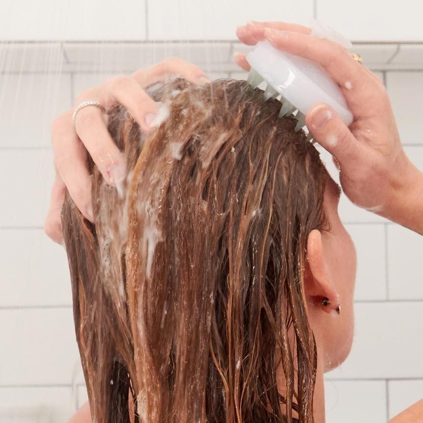 woman using the scalp brush in the shower