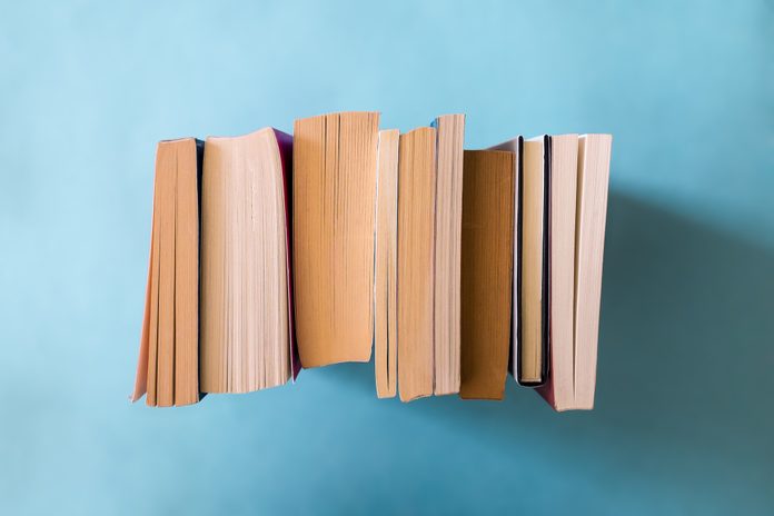 Close-Up Of Stacked Books Against Colored Background