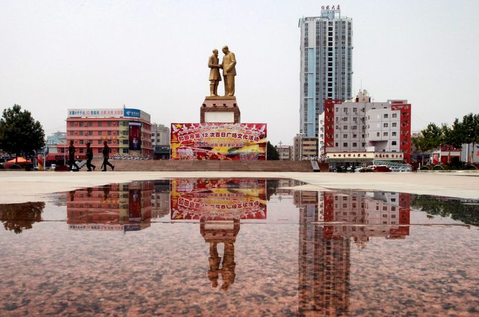 Armed police walk on the Unity Square in downtown Hotan (Hetian), Xinjiang Uygur Autonomous Region. The statue at the back shows Chairman Mao Zedong shaking hands with a common Uygur old man Kuerban, a moment happenedd in Beijing in 1958. 06JUL13 == Pho