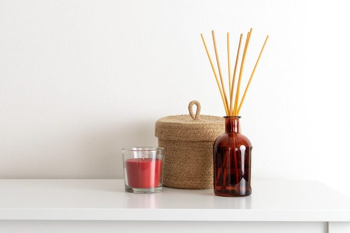 Scandinavian nordic hygge style, home interior - candle, scent aroma diffuser, small straw basket, white shelf