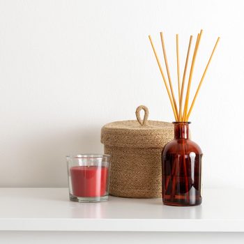 Scandinavian nordic hygge style, home interior - candle, scent aroma diffuser, small straw basket, white shelf