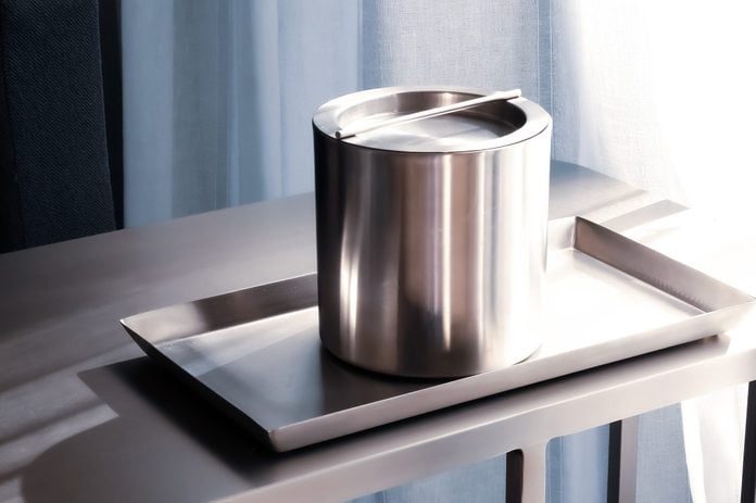 Silver stainless steel ice bucket and tray in hotel room.