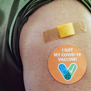 close up of bandaid and sticker on a shoulder; sticker reads, 