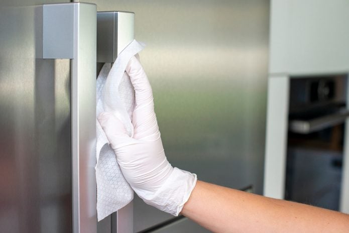 Woman Cleans refrigerator Handle Using Disinfectant Wipe, Coronavirus concept, COVID-19