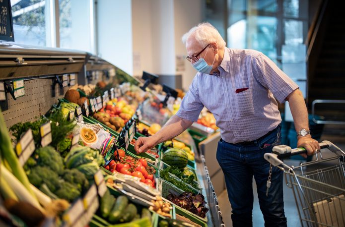 Senior man with face mask buying vegetables in grocery store