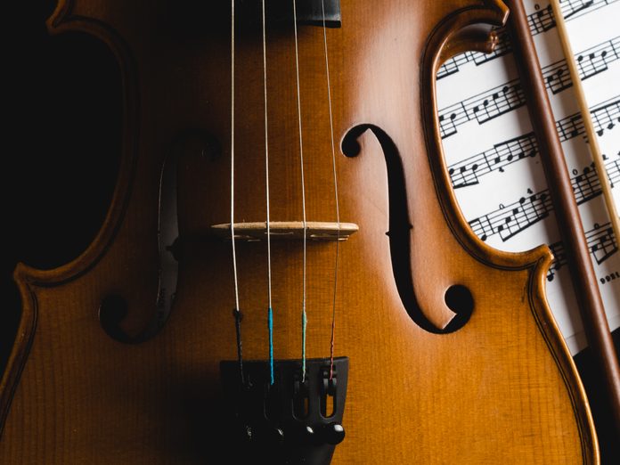 Cropped Image Of Violin against Black Background with sheet music and bow