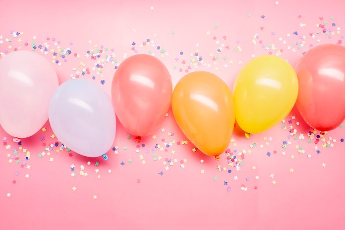 High angle view of colourful balloons in a row on pink background