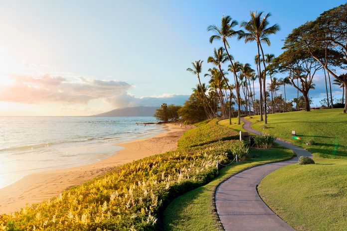 Tropical beach path with palm trees at sunset in the luxury resort destination of Wailea, Maui, Hawaii, USA.