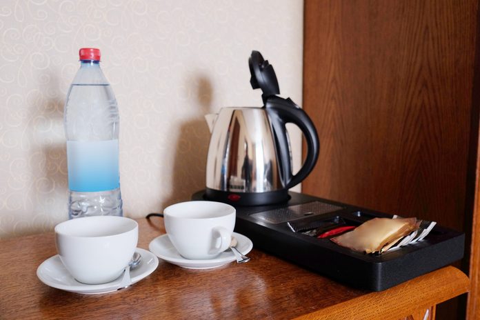 coffee maker in a hotel room next to mugs and a bottled water