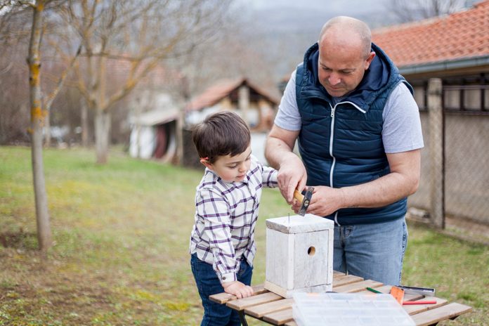Father and son building birdhouse outdoor