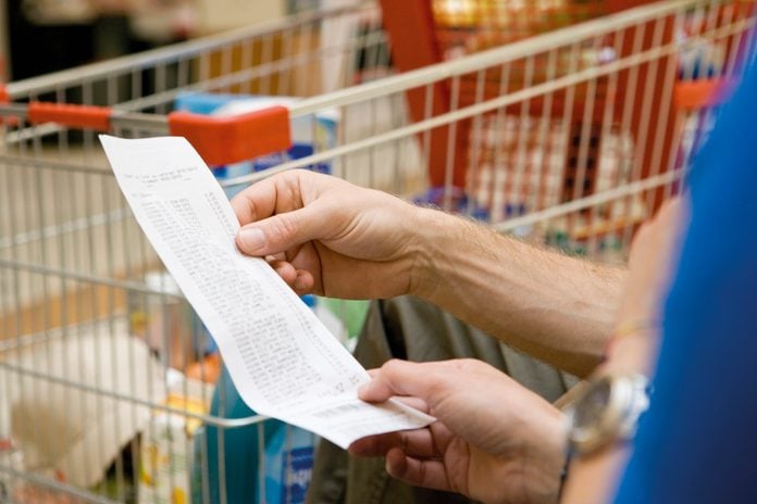Shopper reviewing receipt, cropped