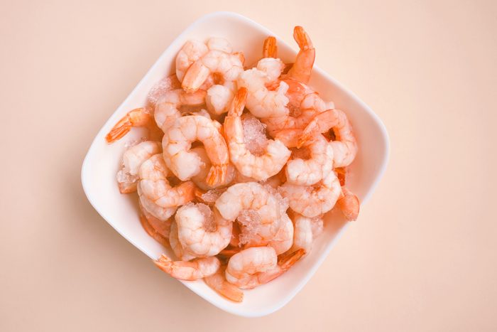 white bowl of shrimp on a light peach colored background