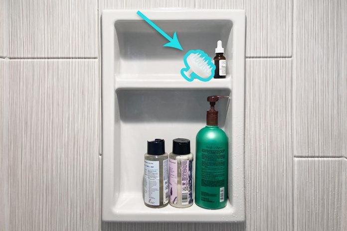 Scalp Brush on a shelf in a shower with other bottles