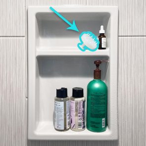 Scalp Brush on a shelf in a shower with other bottles