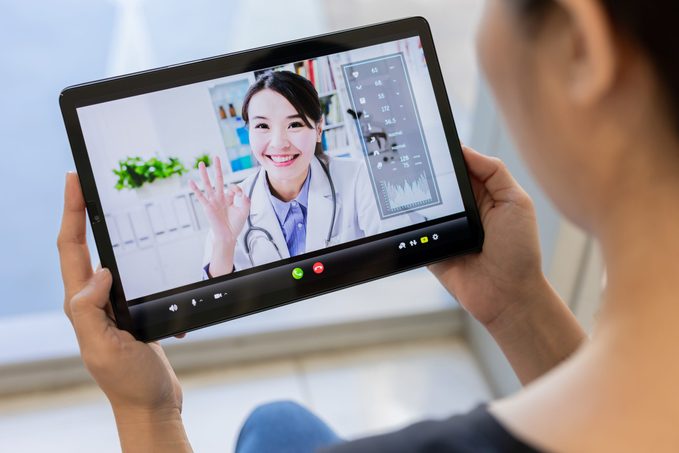 telemedicine concept- patient use tablet to has video chat with asian female doctor