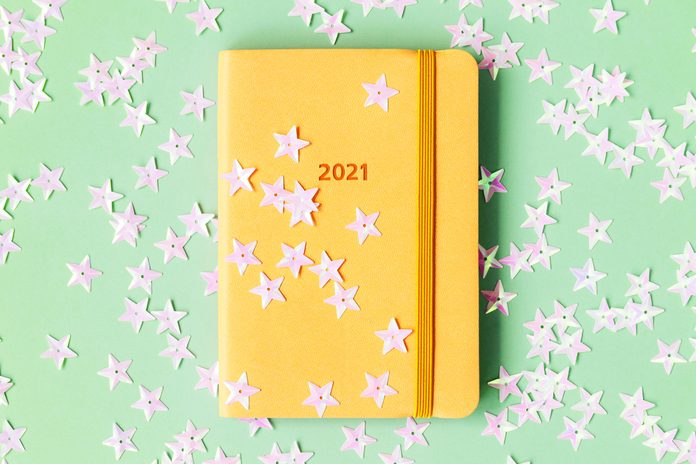 yellow 2021 planner on green background with star confetti