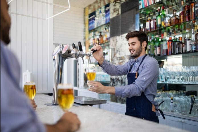 Bartender filing beer in a glass from tap