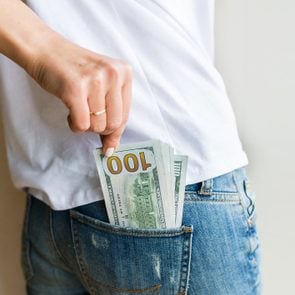 woman got cash money. Richness and wellbeing concept. Get cash money easy and quickly. one hundred dollar bills is in back pocket of jeans. Financial banking, shopping, business concept