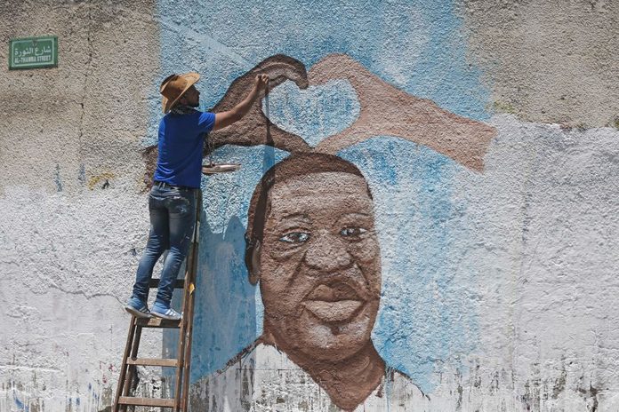 Palestinian artist Ayman al-Housari paints a mural depicting George Floyd in Gaza City on June 16, 2020.