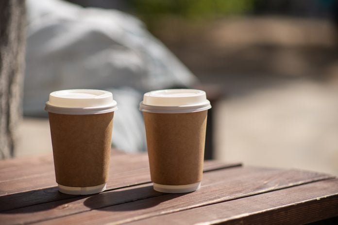Starting day with coffee. two paper cups of latte on creamy blurred background.