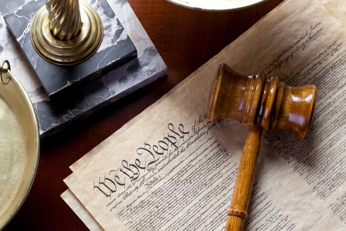 US Constitution with scales of justice and gavel on wood table.