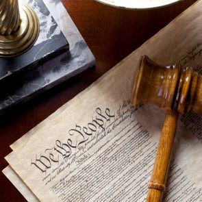 US Constitution with scales of justice and gavel on wood table.