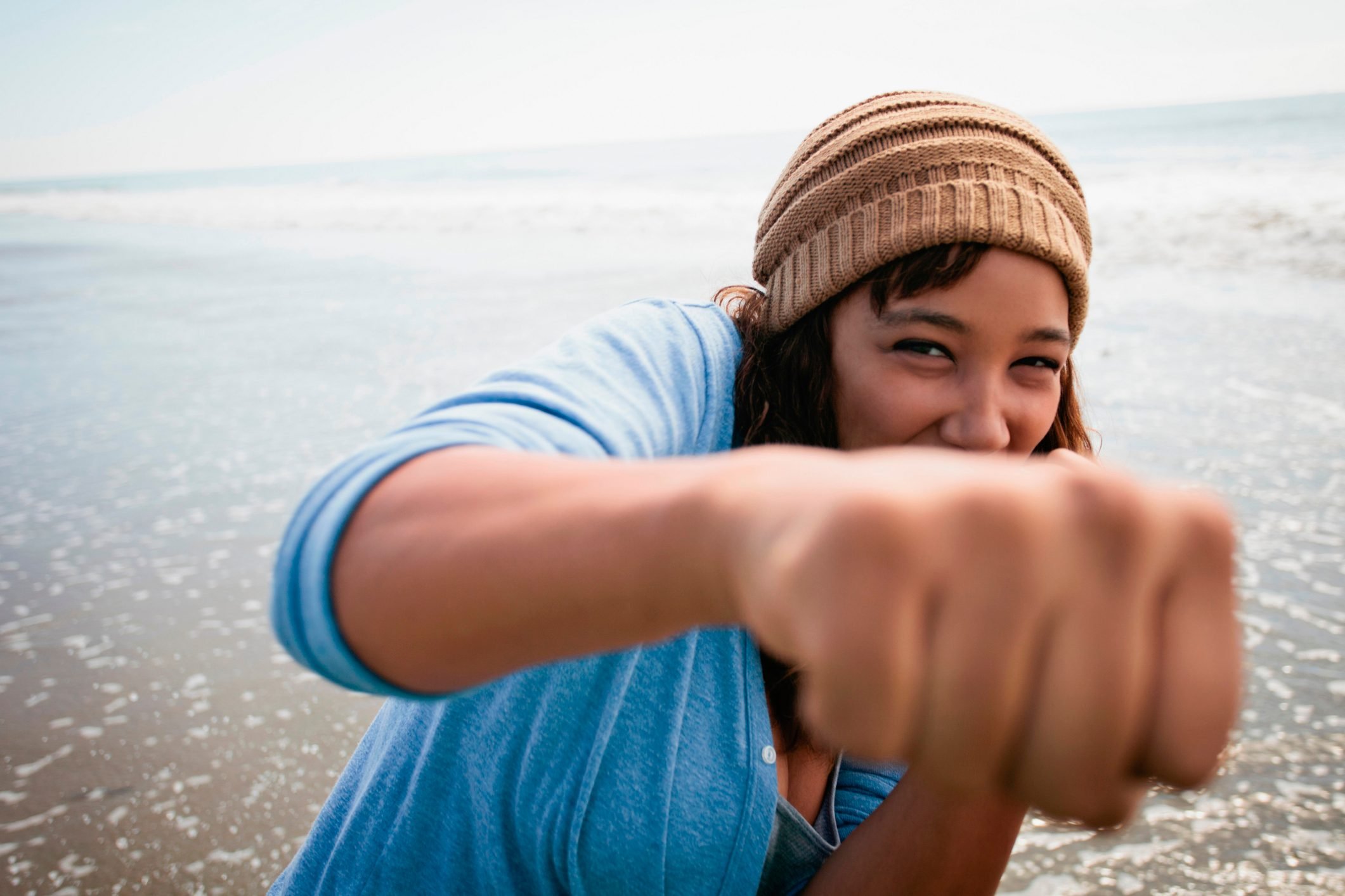 Smiling woman making fists on beach