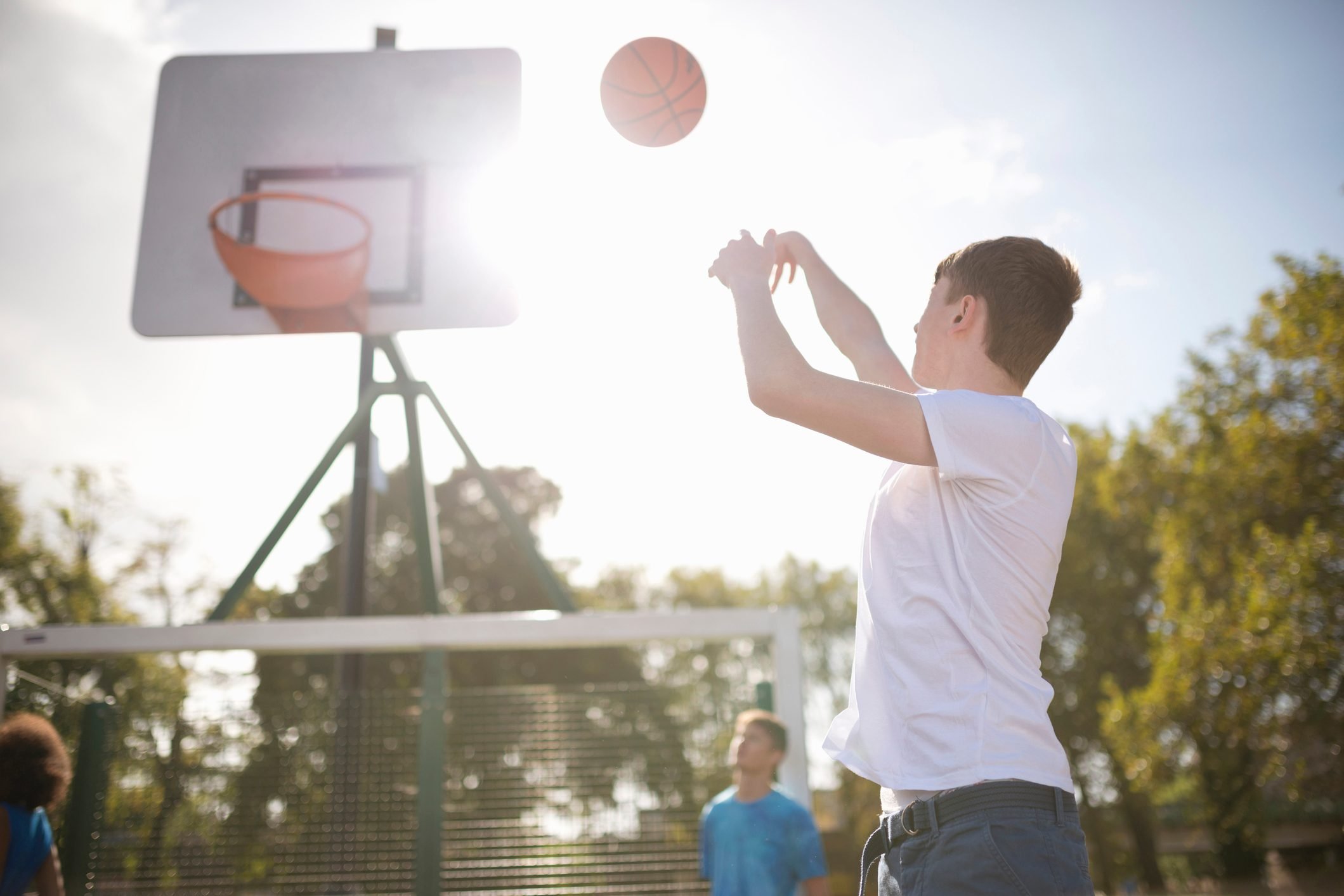 Young male basketball player throwing basketball into hoop