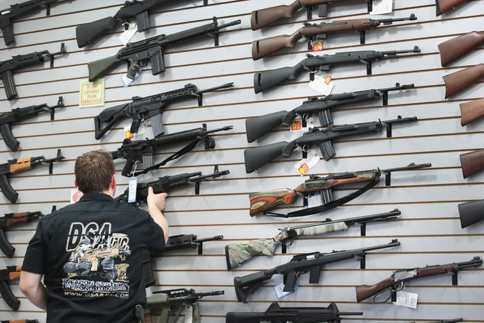guns displayed on a wall in a store with an anonymous gun salesman