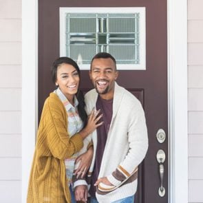 Young mixed race couple standing by front door