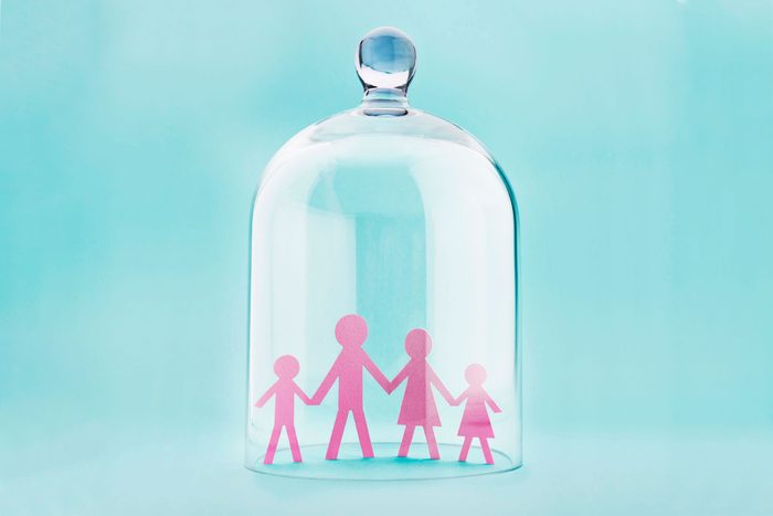 Family silhouette protected under a glass dome on blue background