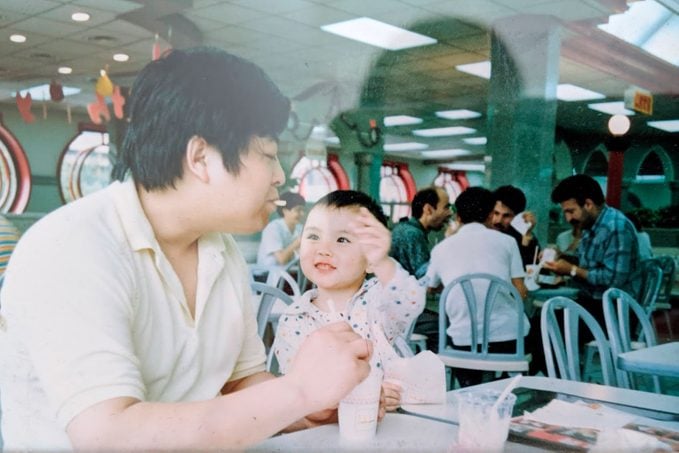 the author, C Pam Zhang, as a young child with her father in a fast food restaurant
