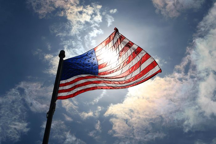 American Flag with the sun shinning through in the background
